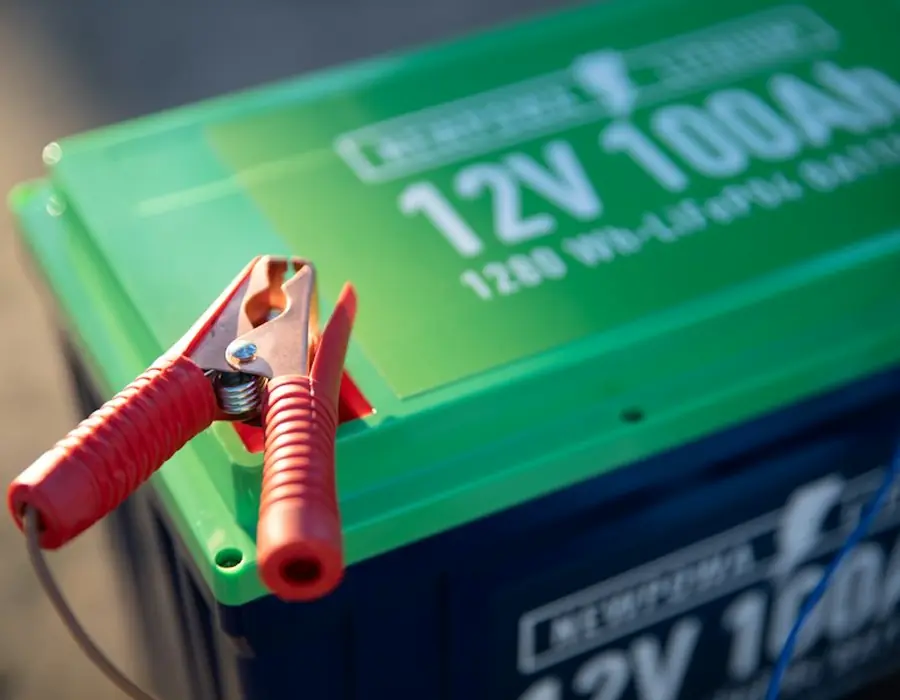 A 12V 100Ah battery with clamps attached
